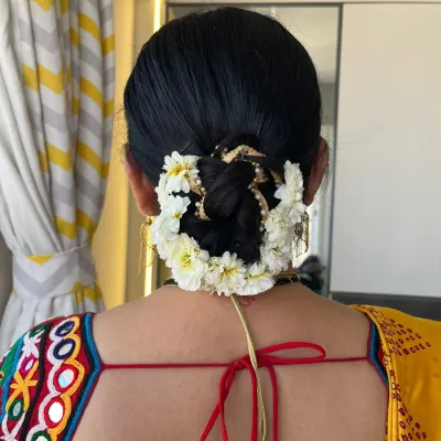 A classic and elegant low bun adorned with fresh white flowers. This timeless hairstyle is perfect for a traditional look with a saree.