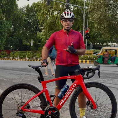 A member posing with his stunning red Pinarello road bike in the middle of a Delhi street.