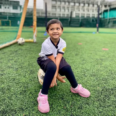 A happy player from our U4 batch takes a break, sitting on his football with a big smile. This image captures the pure, simple joy of our youngest program.