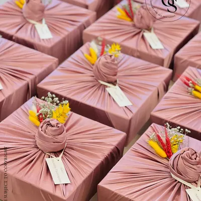 Fabric wrapping adds a layer of luxury and sustainability to any gift. These dusty rose boxes, wrapped in pleated fabric and adorned with dried flowers, are a perfect example of how to make a gift feel exceptionally special and unique.
