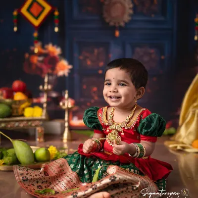 A beautiful smile from a little girl dressed in a traditional South Indian langa voni. The rich colors of her outfit are complemented by the festive backdrop, perfect for celebrating Ugadi or other festivals.