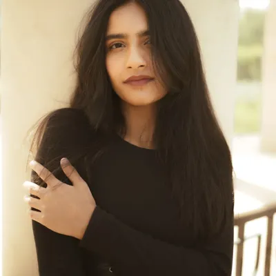A classic portrait using the soft, natural light found in the shade of architectural pillars. The focus is on a clean composition and a genuine expression.