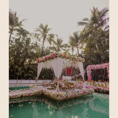 A breathtaking view of a wedding mandap floating on a pool at the Exotica resort in Thane. The floral decorations and serene water create a dreamlike setting for a Maharashtrian wedding.