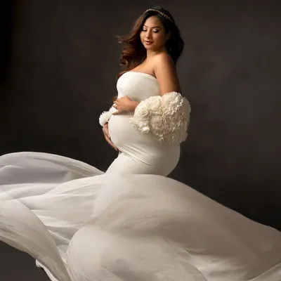 An angelic vision in white. This portrait is all about capturing the serenity and grace of motherhood with a flowing gown that feels as soft and gentle as the moment itself.