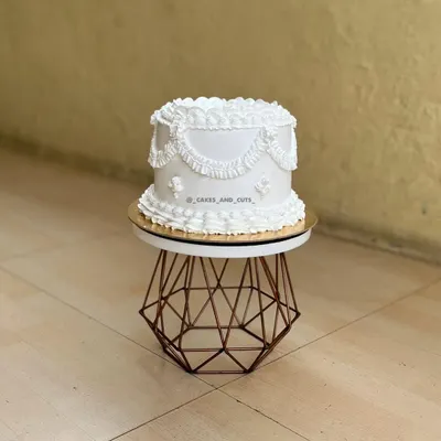 A beautiful all-white vintage cake featuring classic swag piping. This is a perfect example of the skills we teach in our piping-focused workshops.