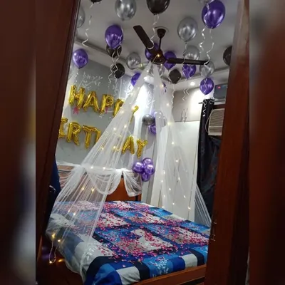 A classic birthday surprise featuring a canopy with fairy lights over the bed, and purple and silver balloons on the ceiling and floor.