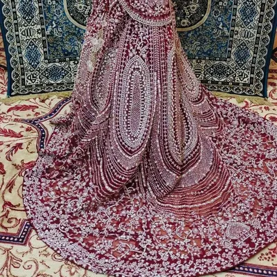 A close-up of the trail of a Pakistani-inspired bridal outfit. The intricate silver and pearl beadwork on the deep wine fabric is absolutely breathtaking.