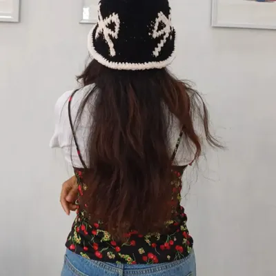 This is a view from the back of my custom crochet bucket hat. It shows how the hat fits and highlights the personalized lettering woven into the black yarn, contrasted by the white scalloped brim.