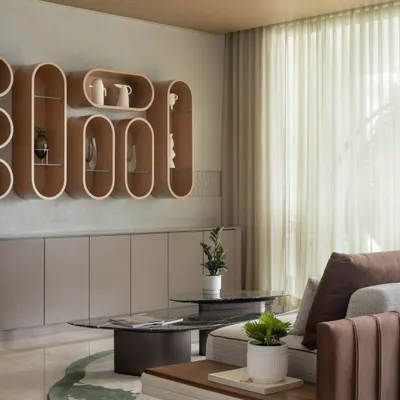 A detail from the Embassy Lake Terraces living room, where sculptural wooden shelves create a unique display. The soft, neutral tones and sheer curtains enhance the feeling of light and space, making it a perfect corner for quiet reflection.