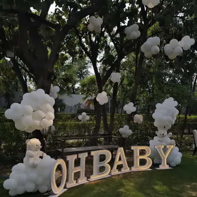 A dreamy outdoor 'Oh Baby' shower with a teddy bear and cloud theme. The large marquee letters and balloon clouds create a beautiful photo backdrop in a garden setting.