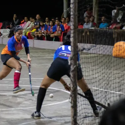 An intense moment from a girls' rink hockey exhibition match, with a player taking a shot on goal as the keeper prepares to make a save. This showcases the high skill level of our female players.