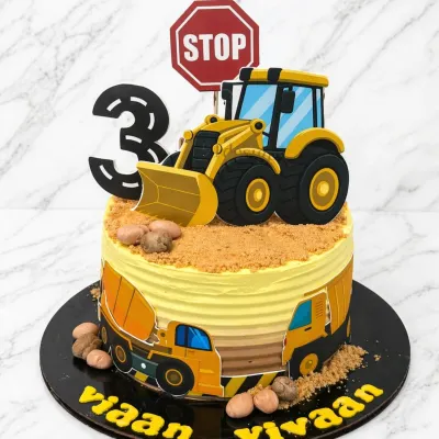 A fantastic bulldozer cake for a 3rd birthday. This design features a detailed bulldozer topper, edible "dirt" made from cookie crumbs, and construction-themed prints around the side.
