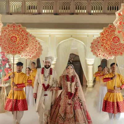 A grand entrance for Rahul and Aashi, walking through a cloud of smoke with traditional umbrellas, creating a truly royal spectacle.