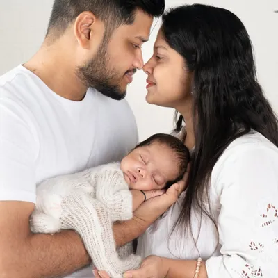 A perfect first family portrait. The baby sleeps peacefully in their parents' hands, a beautiful symbol of how you are their entire world.