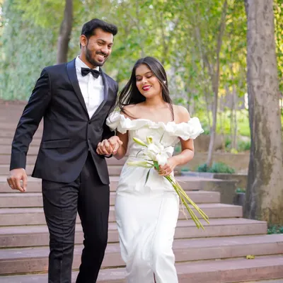 A beautiful, candid shot of a couple in formal attire walking down steps in a lush park. Their smiles and easy movement show the relaxed and happy atmosphere I create during my shoots.