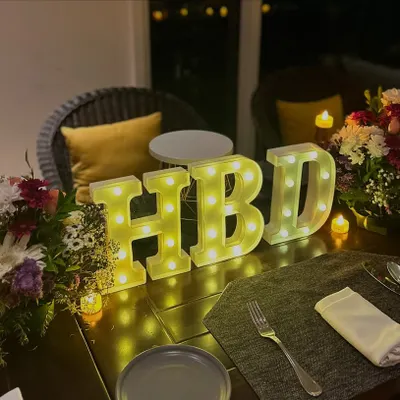 Sometimes, less is more. This minimal table decor with 'HBD' marquee letters, fresh flowers, and candles is perfect for an elegant and intimate birthday dinner.