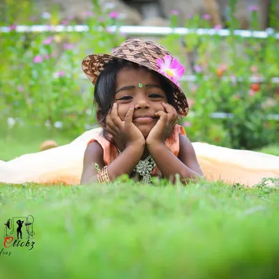 A heartwarming outdoor portrait of a little girl. Lying in the grass with a cute hat, her sweet smile and relaxed pose make for a perfectly natural and adorable photo.