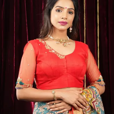 This bright red blouse features sheer sleeves with delicate embroidery at the cuffs, adding a touch of elegance to a bold color.