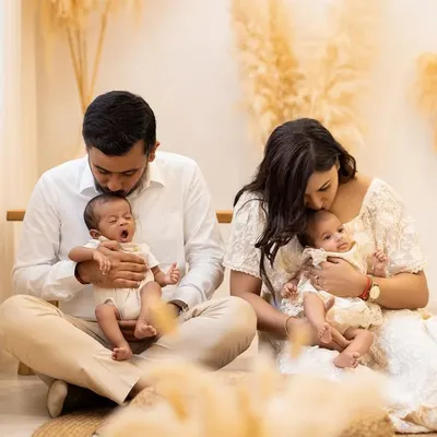 A candid moment of pure love. The new parents gaze at their twin babies, one of whom lets out a tiny yawn. These unscripted moments are what make family newborn photography so special.