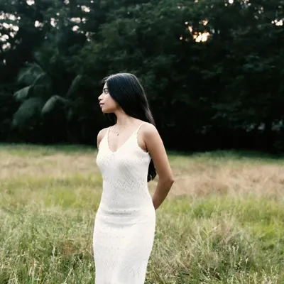 A serene portrait in a field of tall grass. The soft, natural light and the simple white dress create a peaceful and timeless look.