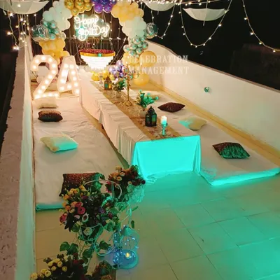 A 24th birthday celebration on a rooftop, complete with low seating for guests, a fairy light canopy, and marquee numbers to mark the special age.