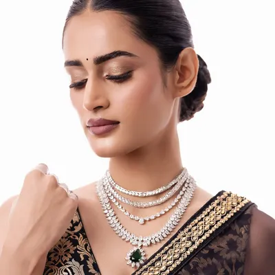 A close-up of a stunning multi-layered diamond necklace with a deep green emerald pendant. This is the epitome of modern glamour, perfect for a reception or black-tie event.