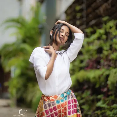 A moment of pure bliss captured outdoors. The soft natural light and the subject's relaxed pose create a feeling of freedom and joy, perfectly contrasting the vibrant skirt with the serene green background.