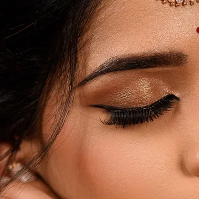 A close up of a classic bronze and gold shimmery eye. This look is perfect for traditional wear, adding warmth and glamour with a sharp winged liner and full lashes.