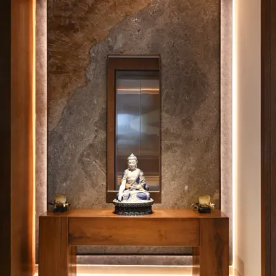 The foyer sets a tranquil tone with a beautiful Buddha sculpture, set against a backdrop of richly textured marble. The design provides a glimpse into the powder room, hinting at the home's cohesive material palette.
