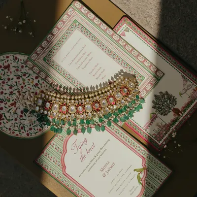 A flat-lay of Mouli and Jaymit's wedding invitation suite, paired with a stunning piece of bridal jewelry. This shot sets the tone for a luxurious and well-curated event.