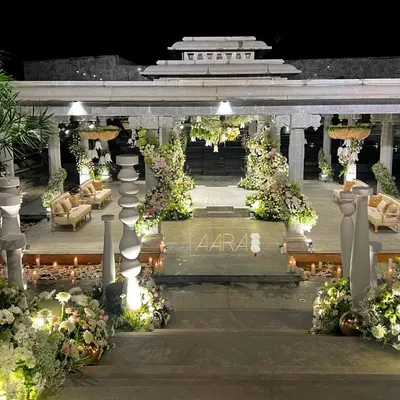 For a modern white wedding at Amita Rasa, I designed this stunning mandap within a stone pavilion. The structure was adorned with cascading white and pink florals, and the aisle was lined with candles, creating a magical ambiance as evening fell.