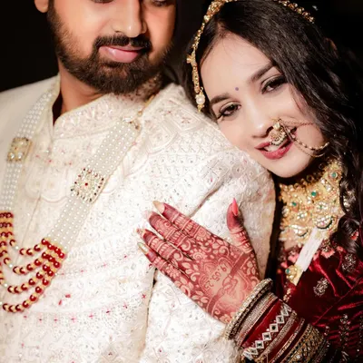 An intimate close-up of the bride resting her head on the groom's shoulder. The focus on her detailed mehndi and the couple's serene expressions makes this a beautifully romantic wedding portrait.