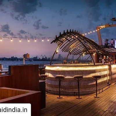 The open-air bar on the upper deck of the Queensline Sea Yah, illuminated at dusk. The design provides an unmatched dining experience with the Mumbai city lights as a backdrop, showcasing a key feature of this unique hospitality architecture project.