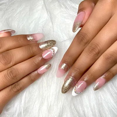 A beautiful set of almond-shaped acrylic extensions. This design features a classic French ombre with a touch of gold glitter and delicate rhinestone accents for a bit of sparkle.