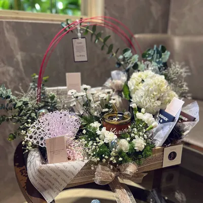 The complete view of a reimagined brand launch gift. Centered around a personalized candle and surrounded by hydrangeas and other curated items, this hamper tells a story of resilience and elegance.