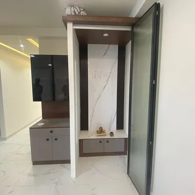 A compact and elegant pooja unit designed with a marble-finish back panel and integrated storage, seamlessly fitting into the home's modern aesthetic.