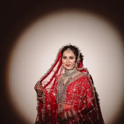 A spotlight moment for the bride. I used dramatic lighting to sculpt this portrait, making her red lehenga and intricate jewelry stand out against the dark, creating a powerful and painterly effect.