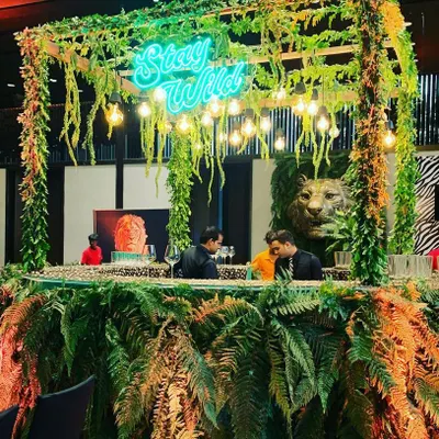 I designed this "Stay Wild" bar for a President's Gala, transforming a standard venue into a lush jungle. The custom neon sign and dense foliage create an immersive atmosphere perfect for a high-end corporate event.