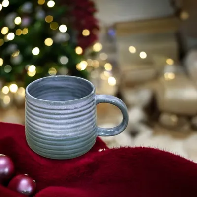 A hand-built stoneware mug with a carved texture and a soft blue-grey glaze. A handmade mug makes your morning coffee or tea feel a little more special, and they make wonderful, personal gifts.
