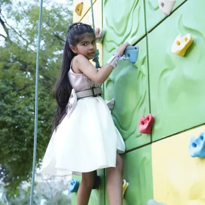 Adventure comes in all forms, even in a party dress! This young climber shows her strength and determination on our colorful outdoor climbing wall.