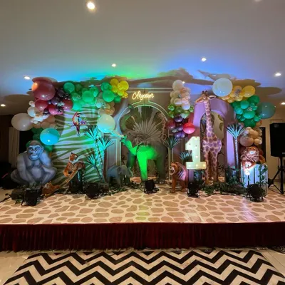A spectacular 'Wild One' jungle safari stage. I used life-sized props of a gorilla, elephant, and giraffe, along with a custom printed floor and a lush balloon garland to create this immersive scene.