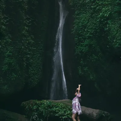 Chasing waterfalls and adventures in Bali. This wide shot captures the immense scale and beauty of the Leke Leke waterfall, with my wife standing in awe of the magnificent natural surroundings.