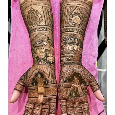 A grand and regal mehendi design for an engagement ceremony. It features portraits of the couple set against a backdrop of palace architecture, making a stunning statement.