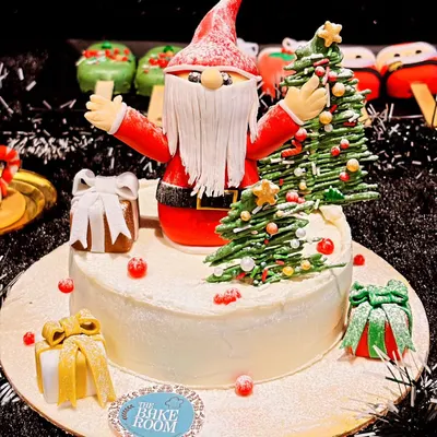My centerpiece Christmas cake featuring a handcrafted Santa Claus and a Christmas tree. This cake is surrounded by festive details like gift boxes and is perfect for a large family gathering.