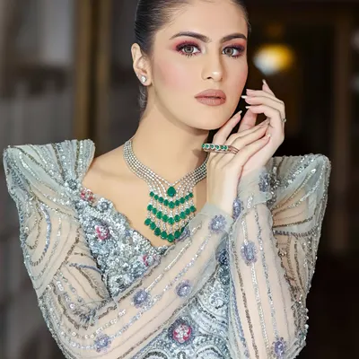 A stunning portrait showcasing a complete bridal jewelry set, including a multi-layered emerald necklace and matching ring. The lighting is precisely controlled to make every gem and detail stand out.