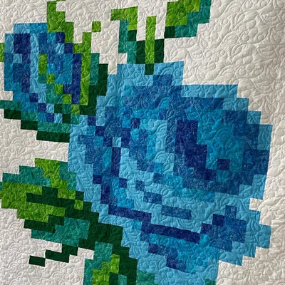 A close-up of a pixelated rose quilt, showing how the small squares of fabric come together to form a larger image.