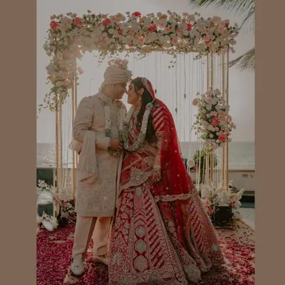 A picture-perfect moment from a Goa beach wedding. The floral arch, the sea in the background, and the happy couple create a stunning frame that perfectly captures the dream of a destination wedding.