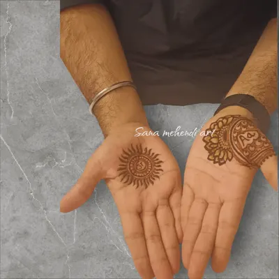 A simple and traditional mehendi for the groom, with a sun motif on one palm and the sacred 'Om' symbol on the other.