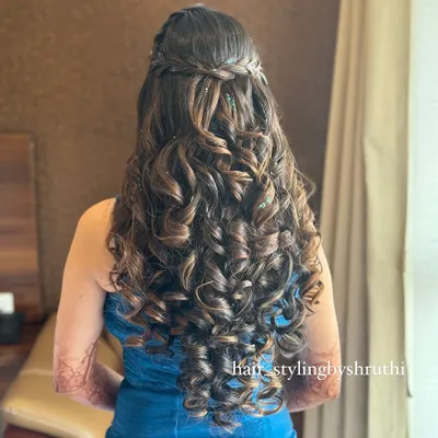 A half-up hairstyle with a crown braid and a cascade of tight, defined curls. This look is perfect for adding texture and volume, suitable for a sangeet or reception.