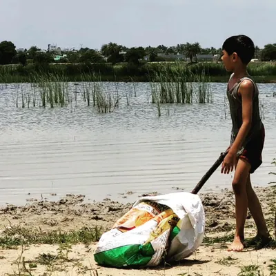 A child transports a heavy bag of freshly harvested clay from the lake bed. This is the first step in our earth-to-art process, connecting hard work with creative reward.